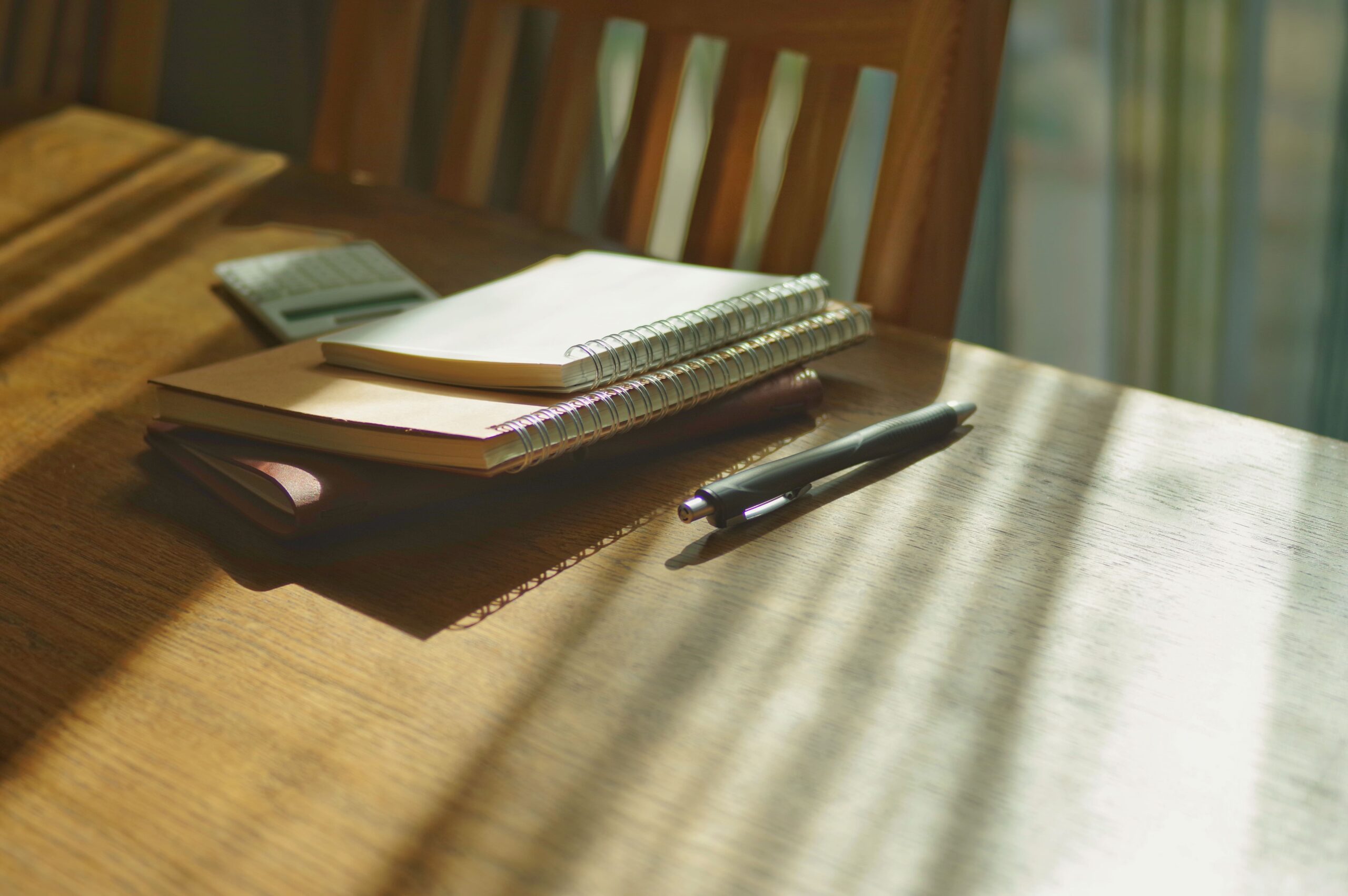 書類とペンを前に、資料を整理する喪主のイメージ。葬儀後の手続きと心のケアを両立する時間を象徴