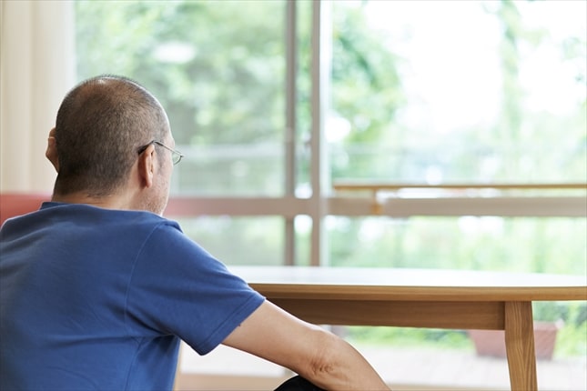 葬儀を終え窓辺で静かに佇む喪主の後ろ姿。葬儀後の“心の変化”と、自分自身のケアを思い出す時間を象徴