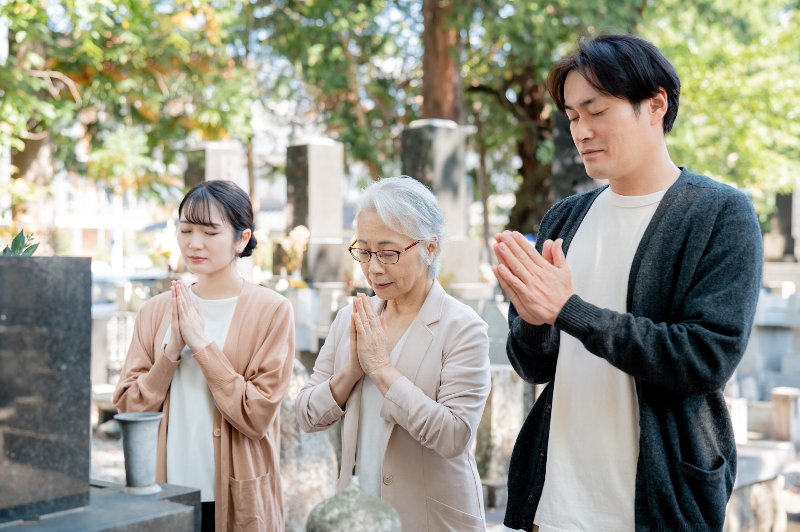 墓じまいを考える家族がお墓の前で悩んでいる様子（少子高齢化や継承問題のイメージ）